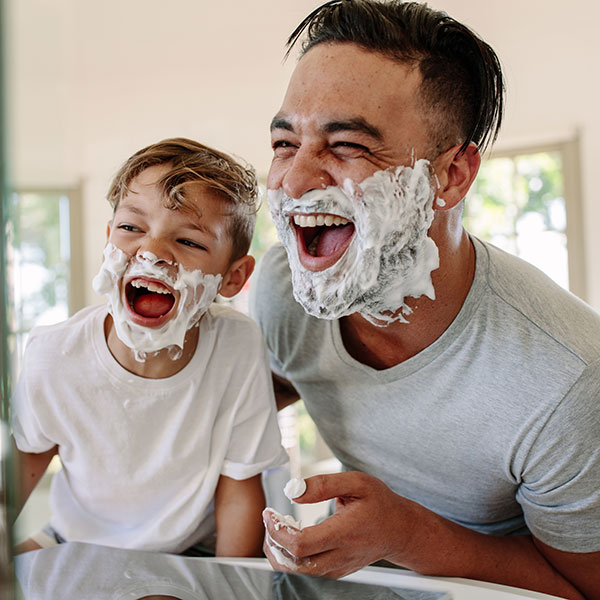 Vater und Sohn mit Rasieschaum im Gesicht
